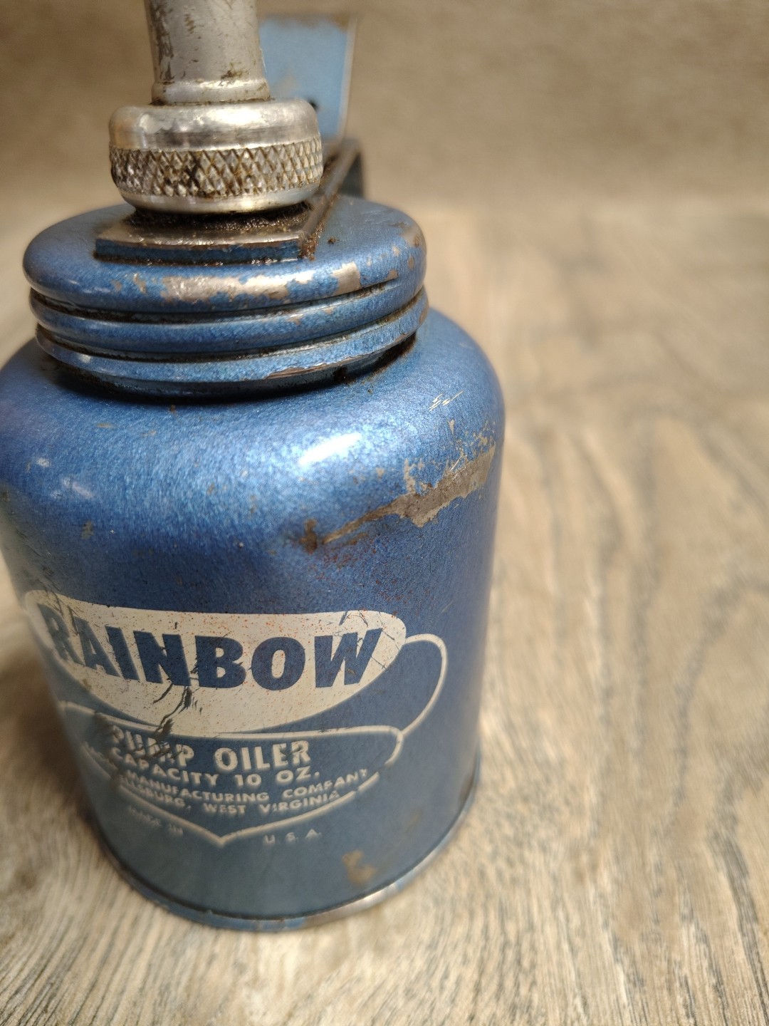 Vintage Plews metal pump oil can featuring a long rigid spout and classic thumb